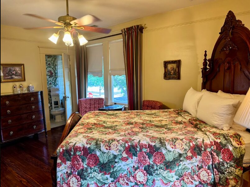 A Daisy Polk Inn guest room with a carved antique bed and floral coverlet